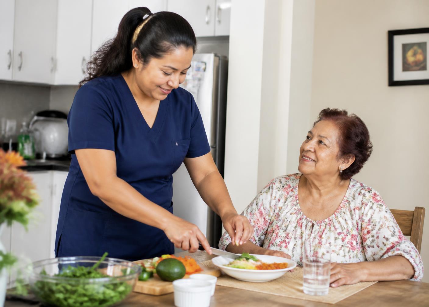 Aide preparing a meal with a smiling senior woman in her kitchen